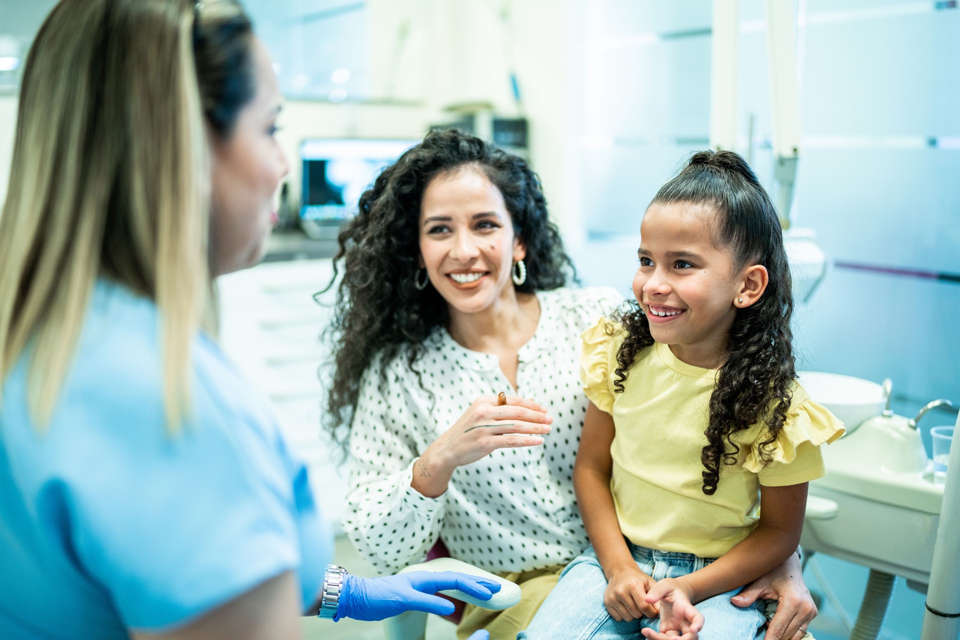 Dentist talking to mother and daughter patients in her office