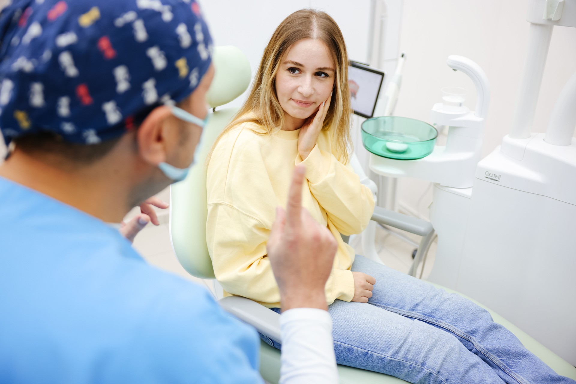 Young woman feeling pain, holding her cheek with hand at dentist's office.Toothache concept.